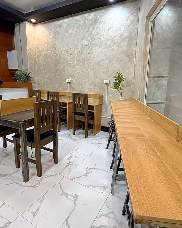 Long wooden counter by the window with stools beside the study desks